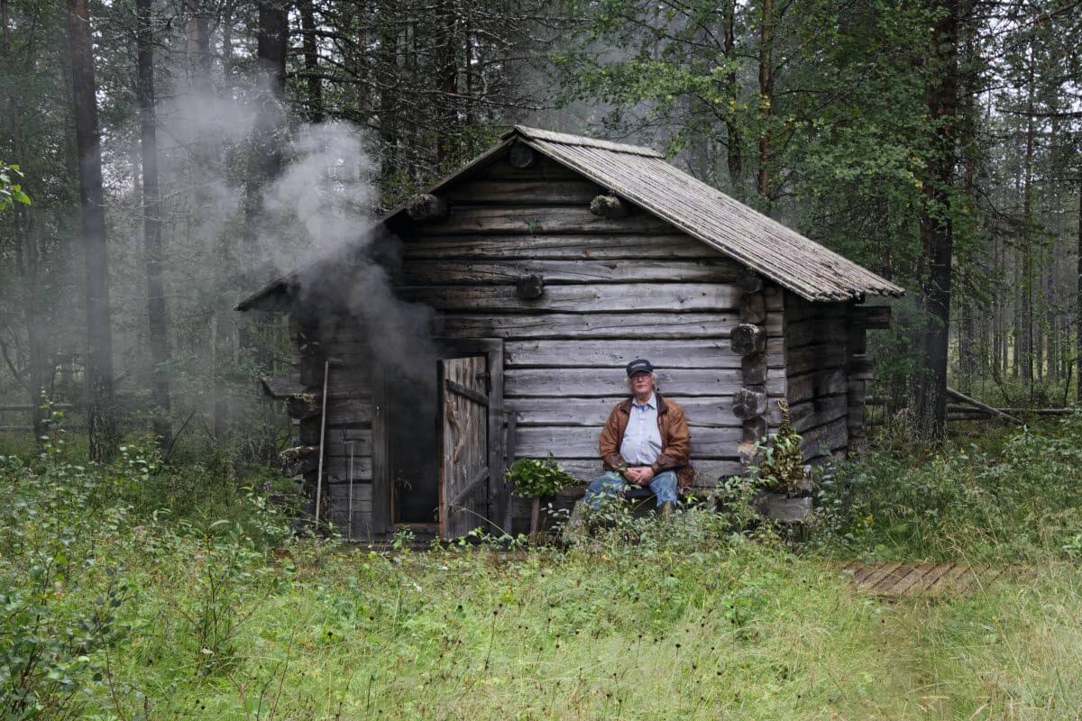 Tapani Hietanen yli sata vuotiaan savusaunan lämmityspuuhissa. Sen löylyissä ovat viihtyneet talon väki, kenraali Wallenius ja monet muut. Kuva: Raija Hentman.
