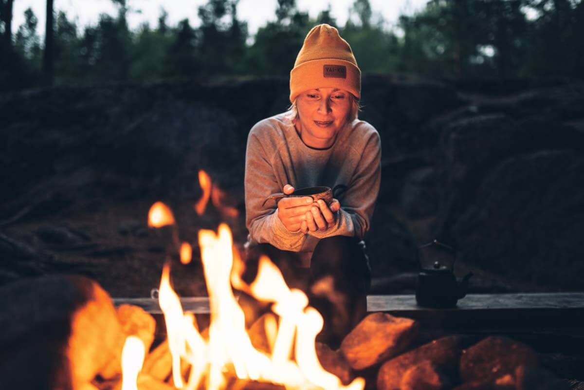 Erä- ja luonto-opas Lennu Heikkinen nauttii iltateetä tulen äärellä Liesjärven Siltalahden tulipaikalla. Hän on kulkenut puiston lähes jokaisen reitin, ja palaa sinne aina mielellään uudelleen.
