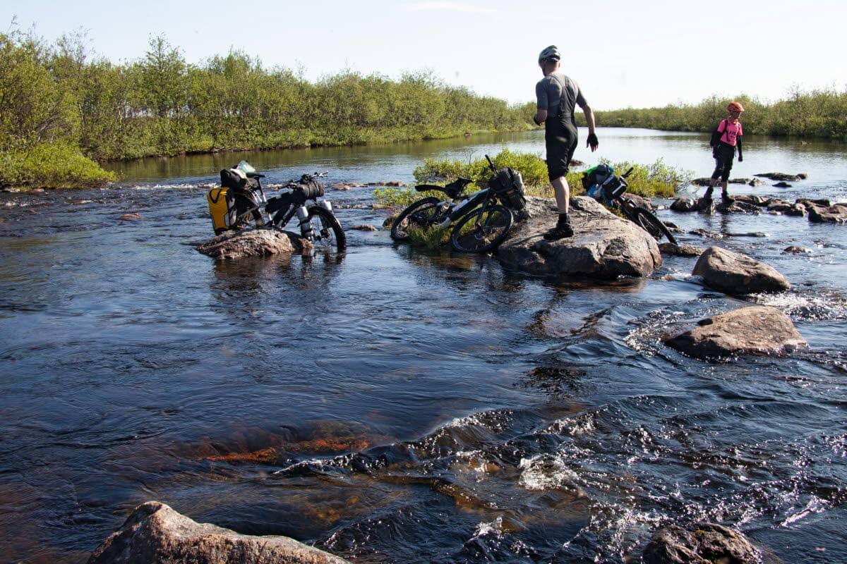 Kaukana erämaassa maastokartat ja reittimerkinnät maastossa voivat aiheuttaa yllätyksiä. Joen ylittäminen Mollešjohkassa ei merkintöjen mukaan pitänyt olla läheskään niin vaativa homma, että joudutaan kahlaamaan sähköpyörät selässä vyötärön syvyisessä vedessä. Kuva: Sauli Herva.