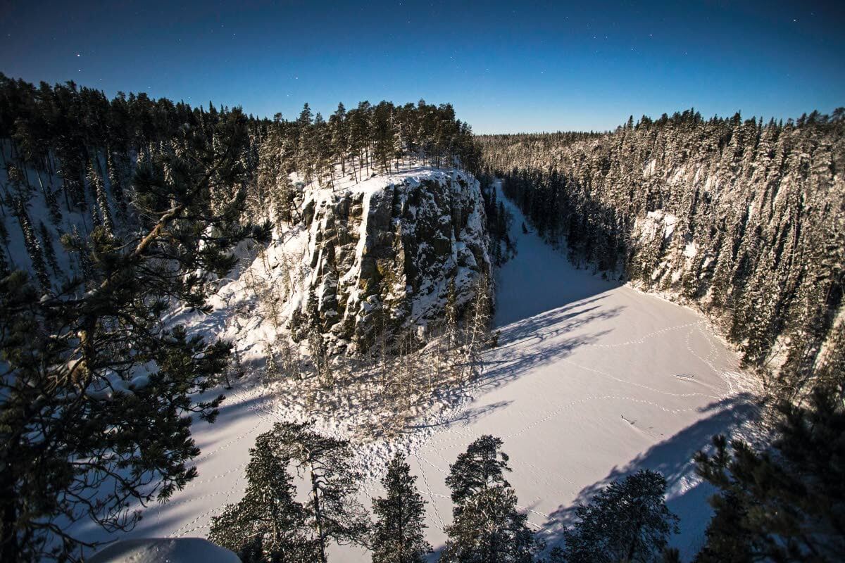 Ristikallio kuun valossa. Porot ovat jättäneet jälkensä jäälle