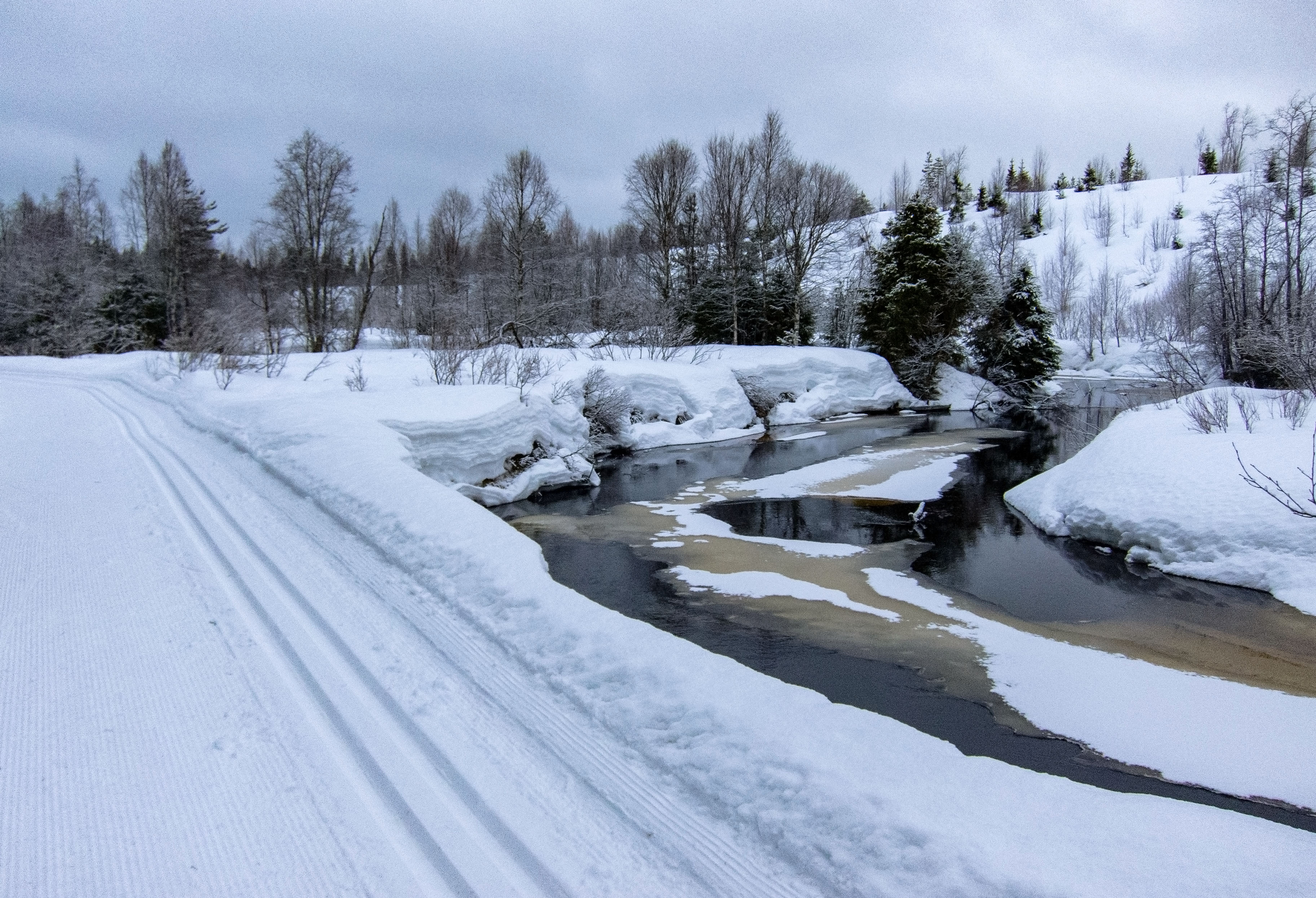 Talven lumenkertymä näkyy poikkileikkauksena jokitörmällä. Paljakka on Suomen lumisinta seutua.