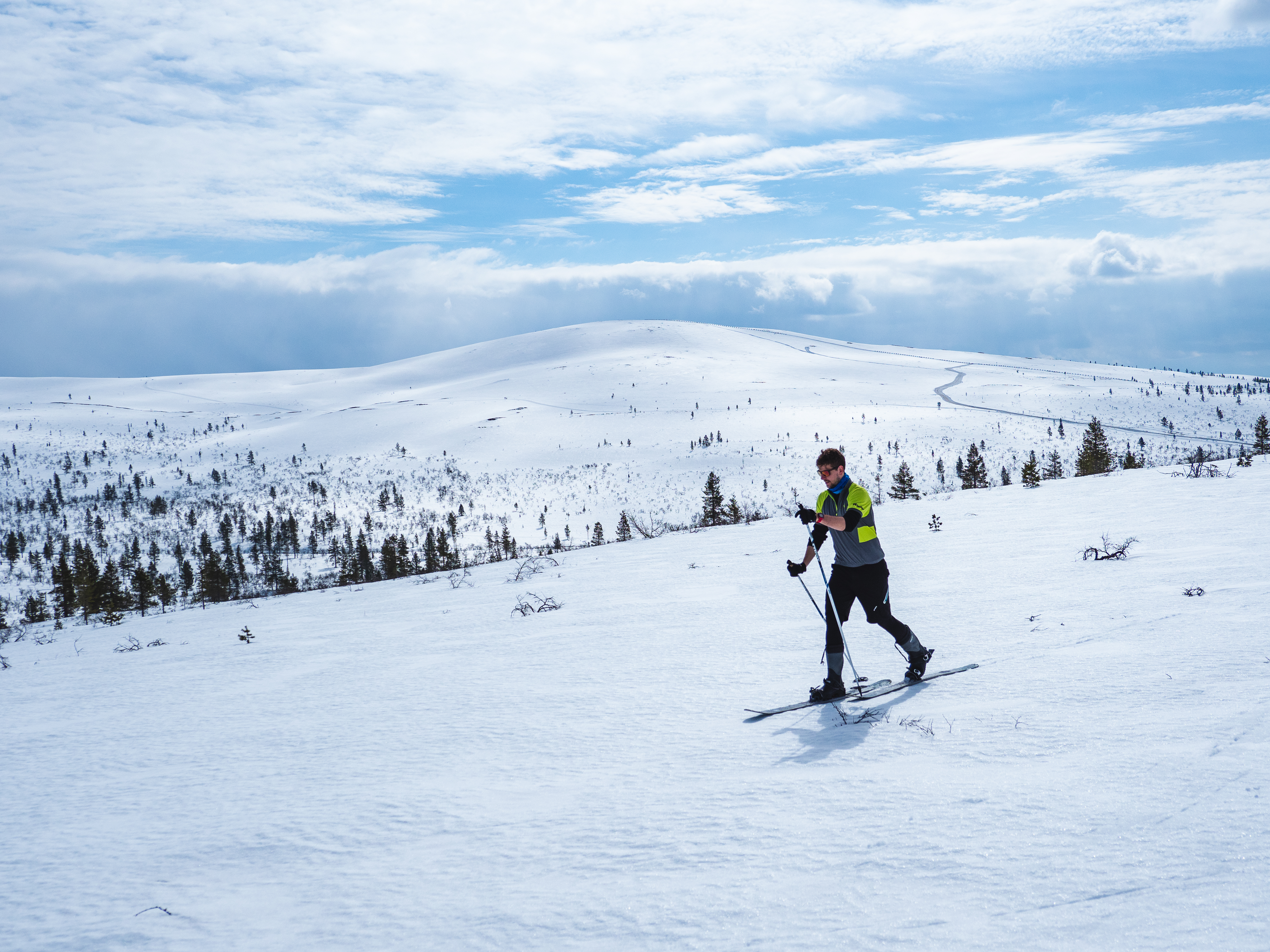 Tunturihiihtäjä Ahopään läntisimmän huipun rinteellä. Taustalla Kiilopää sekä Luulammen latu. Kuva: Sampsa Sulonen.