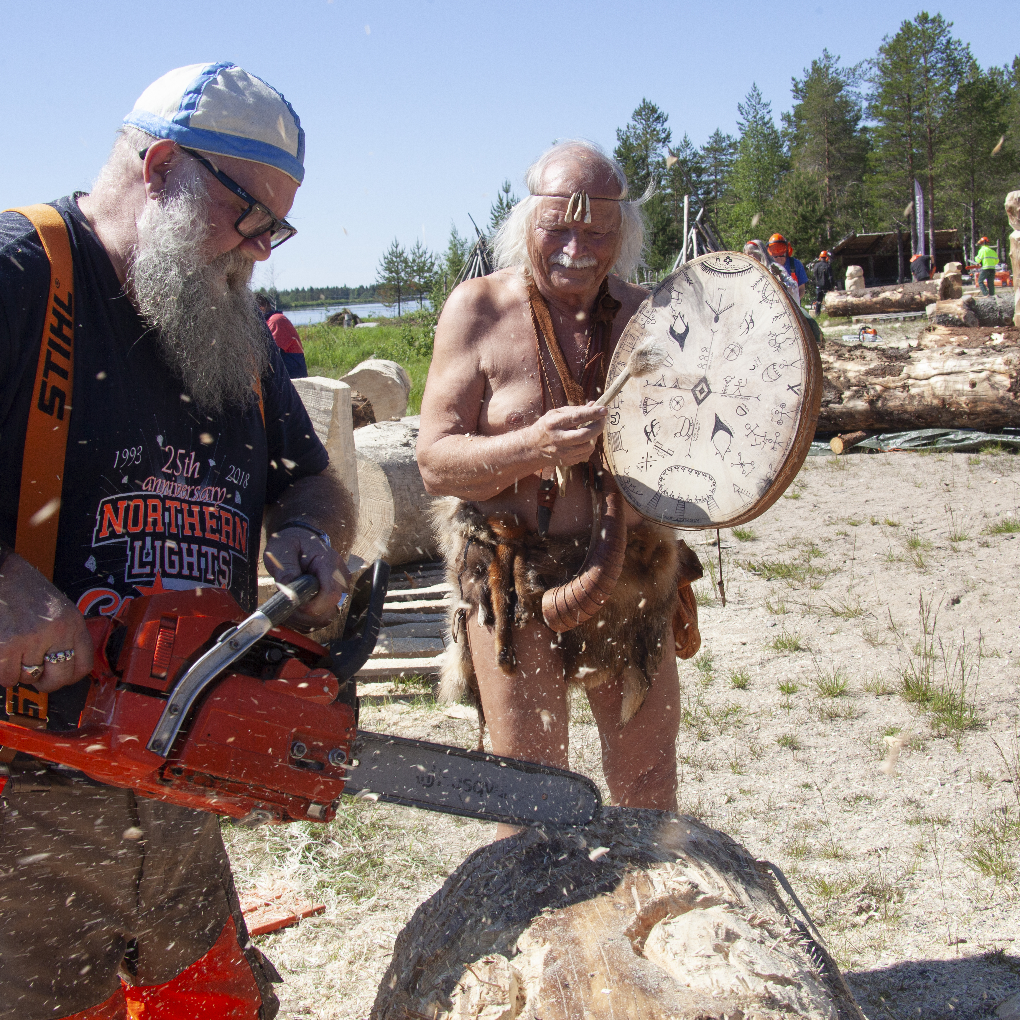 ”Siuruan tasavallan suurmies ja päämies”, monitaitelija ja julkkis Kari Tykkyläinen (vas.) opettaa moottorisahaveistokurssilla Yli-Iin Kierikkikeskuksessa. Vieressä keskuksen vapaaehtoinen työntekijä pukeutuneena kivikauden henkeen. Kuva: Sauli Herva.