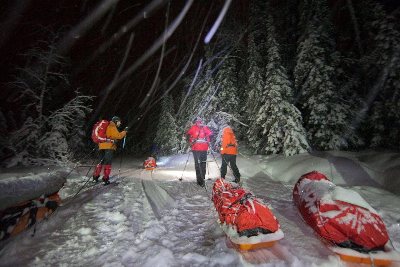 Murtomaita kaamoksen pimeydessä puhkovat retkihiihtäjät etenevät lumituiskun keskellä otsalamppujen valossa.