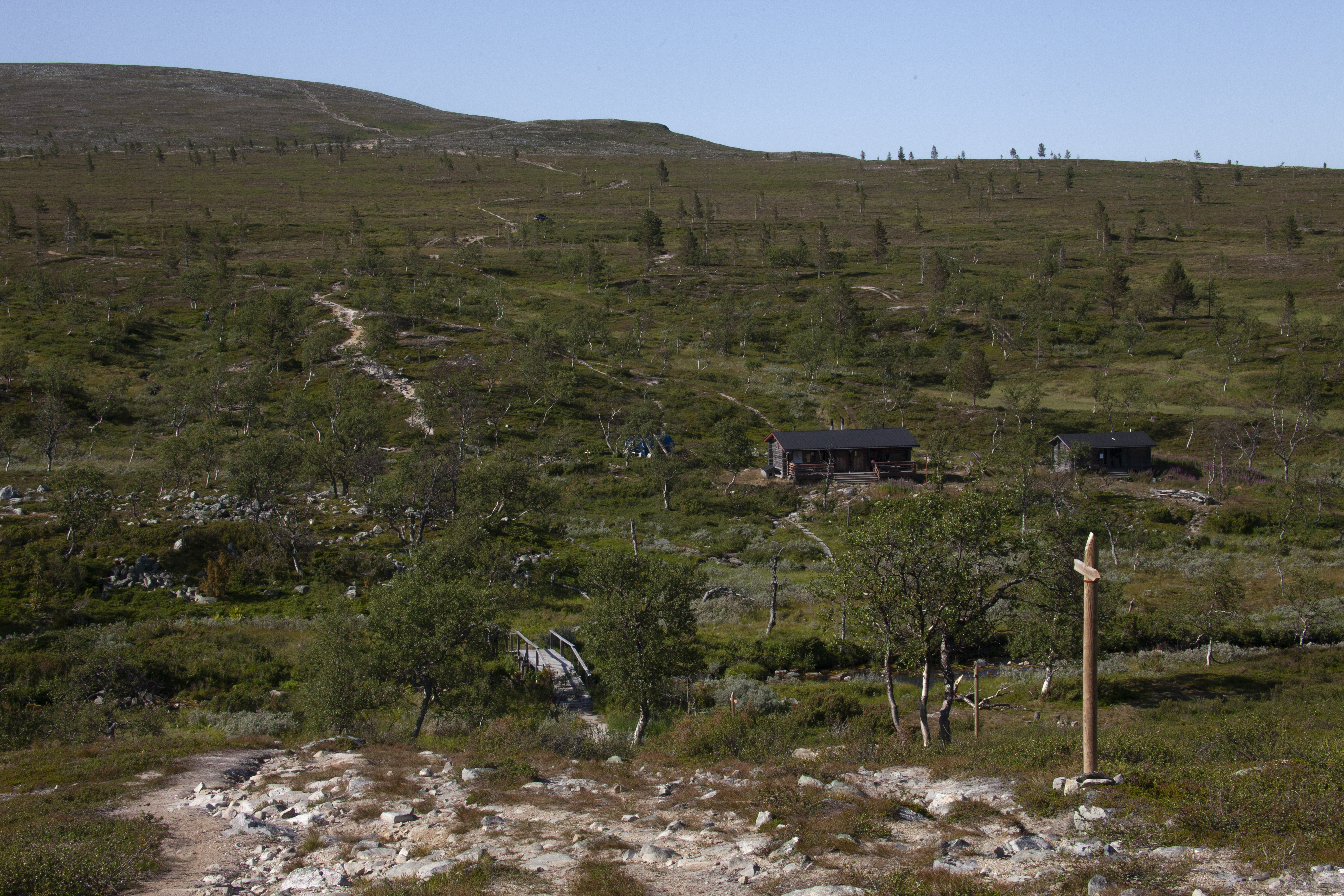 Aika ajoin vilkas Sioskurun kämppä seisoo rehevässä ja suojaisessa notkelmassa Siosjoen äärellä. Kämpän ympäristö on kulunut ja ehkä vähän rähjäinenkin.  Kuva: Sauli Herva.